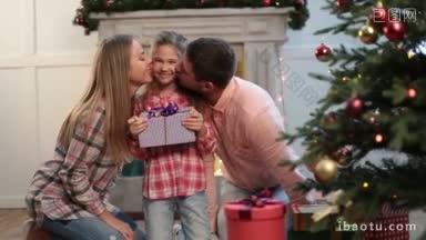 可爱的父母亲吻快乐的女儿在<strong>圣诞</strong>装饰的房间可爱兴奋的小女孩拿着<strong>圣诞</strong>礼盒和深情的父母